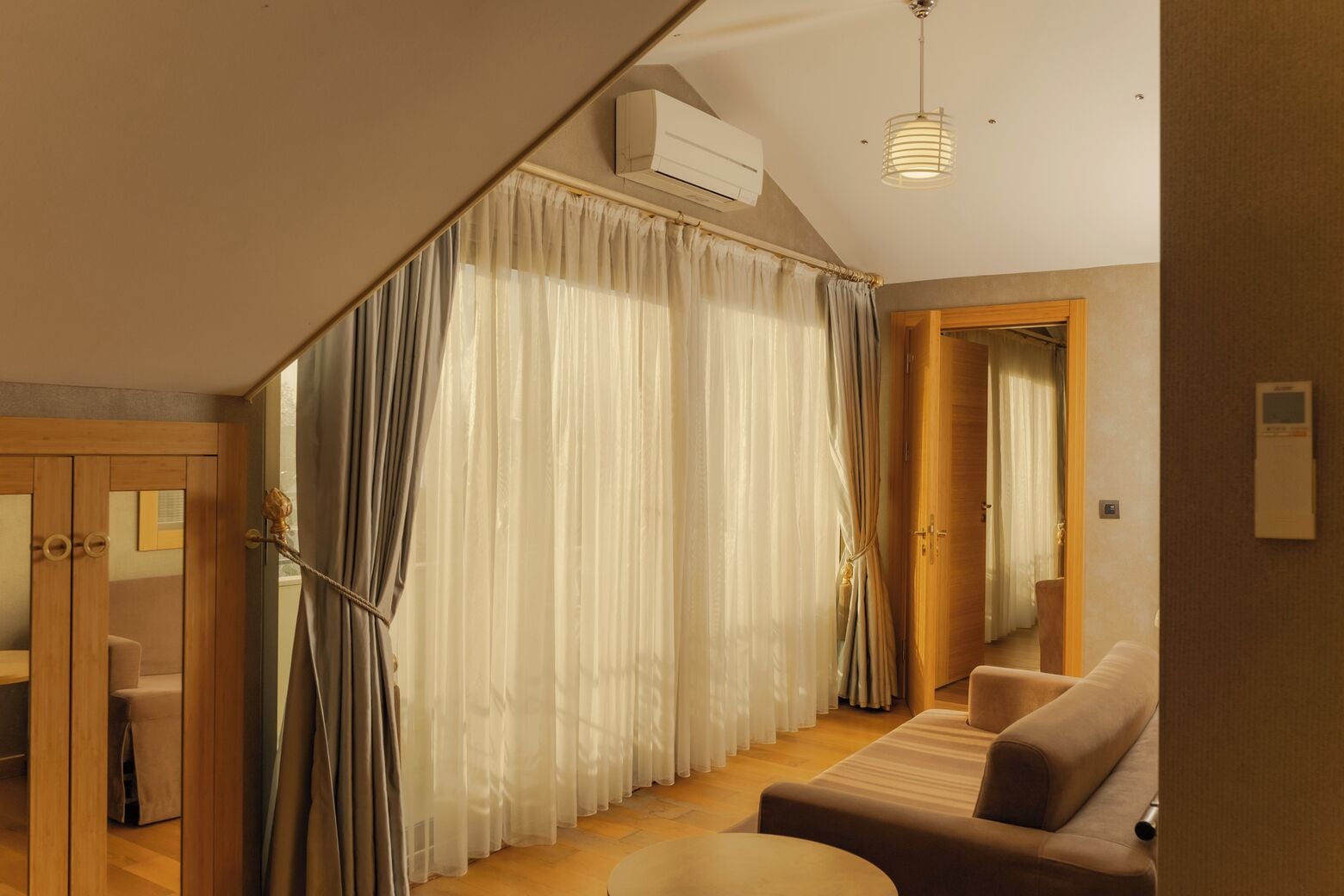 Una sala moderna con un sofá, una mesa de comedor y una escalera con cortinas.