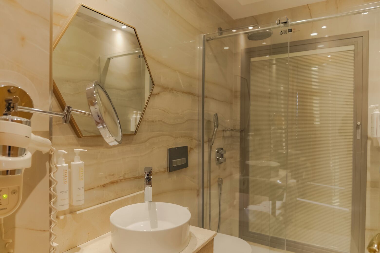 Un baño moderno con un lavabo redondo, un espejo grande y una ducha con cerramiento de vidrio.