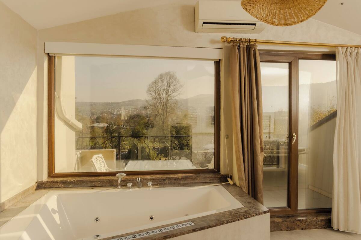A bathroom with a large window, a bathtub, and a sliding glass door.