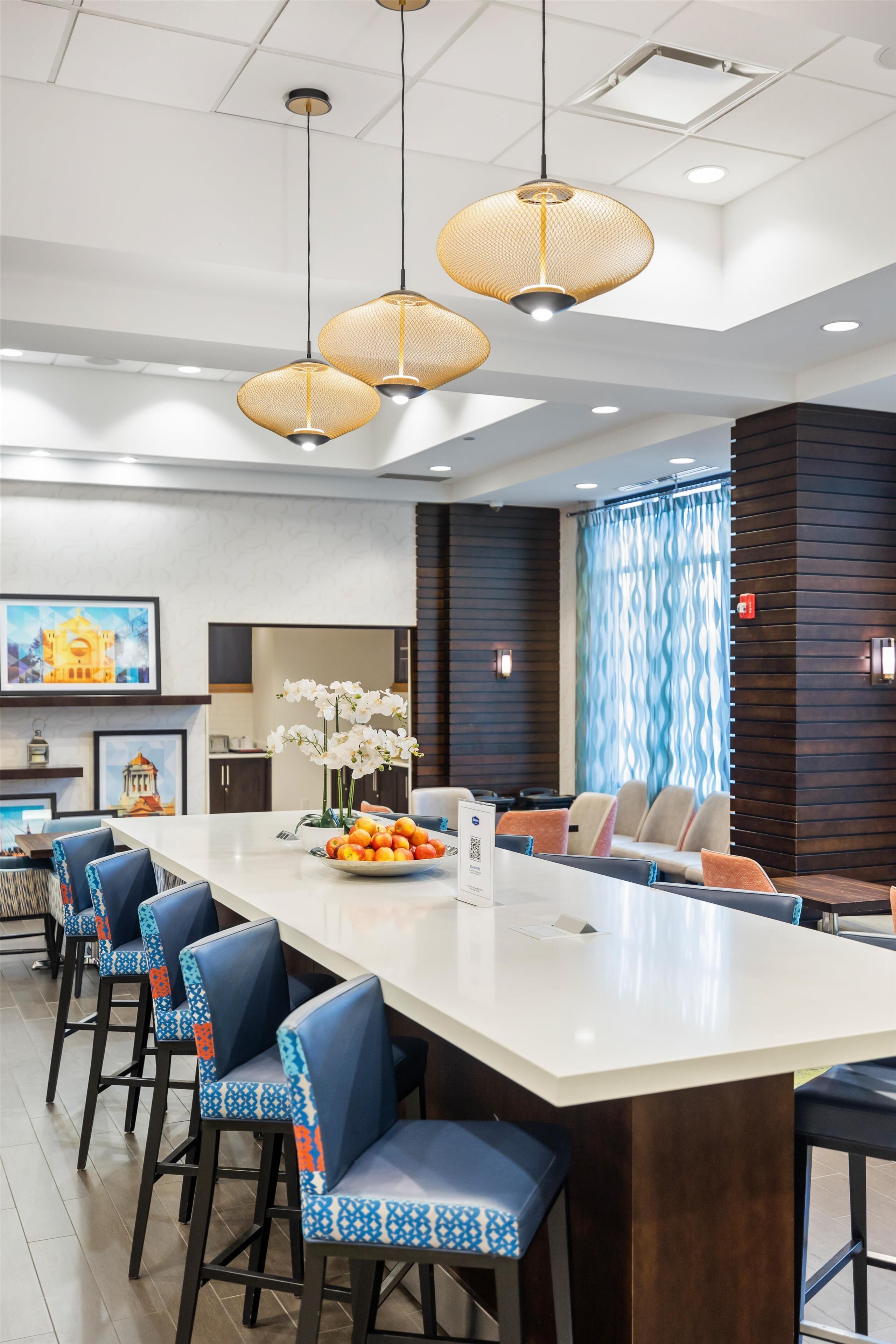 A modern kitchen with a central island, bar stools, and hanging pendant lights.