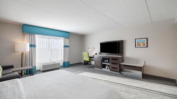 A hotel room with a bed, a desk, a television, a chair, and a picture on the wall.