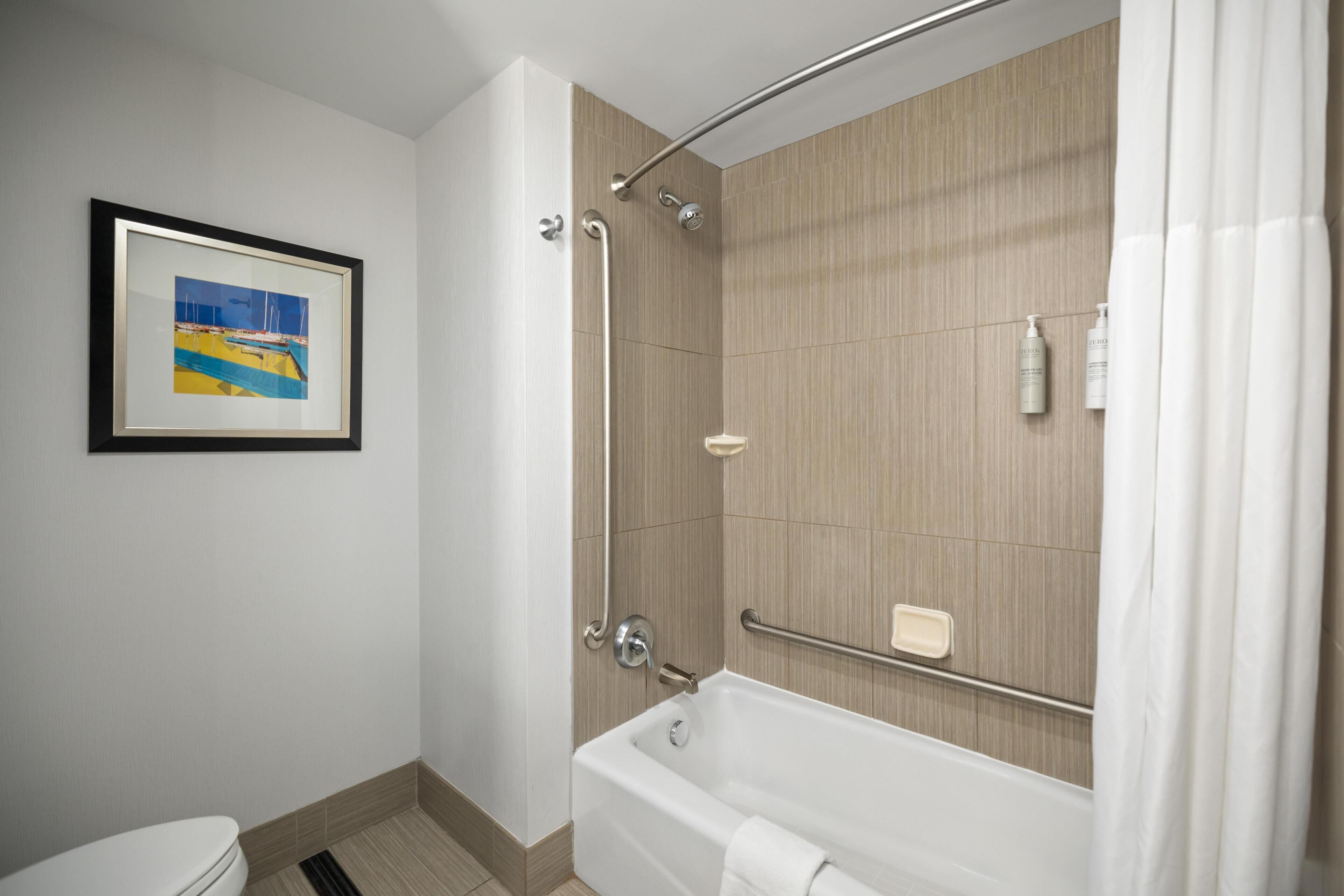 A modern bathroom with a bathtub, shower, and toilet.