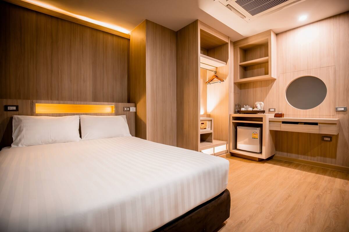 A hotel room with a bed, built-in wardrobe, and a small kitchenette.