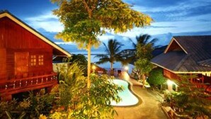Un edificio de madera con piscina y vegetación tropical.