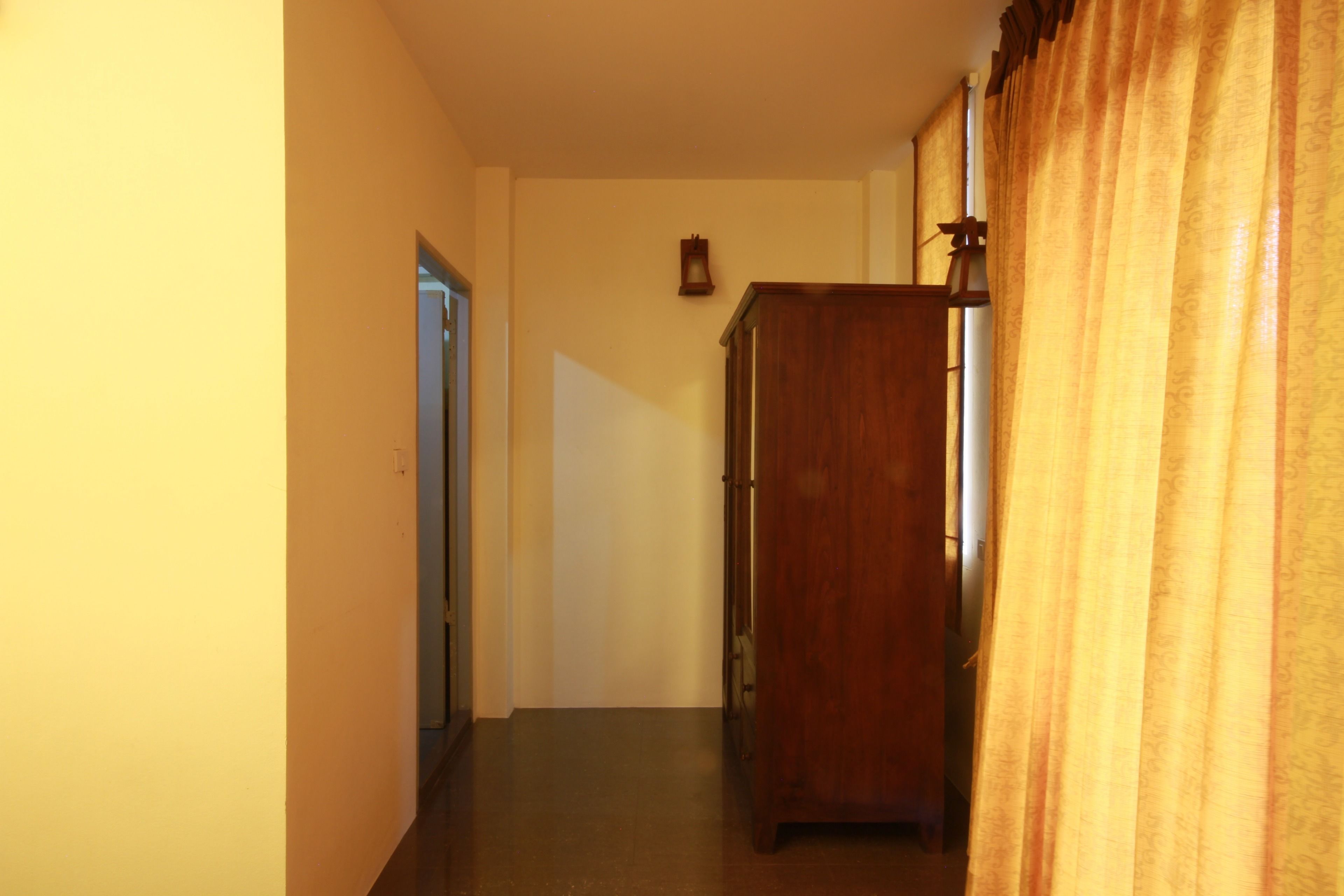 A narrow hallway with a wooden cabinet and a door at the end.