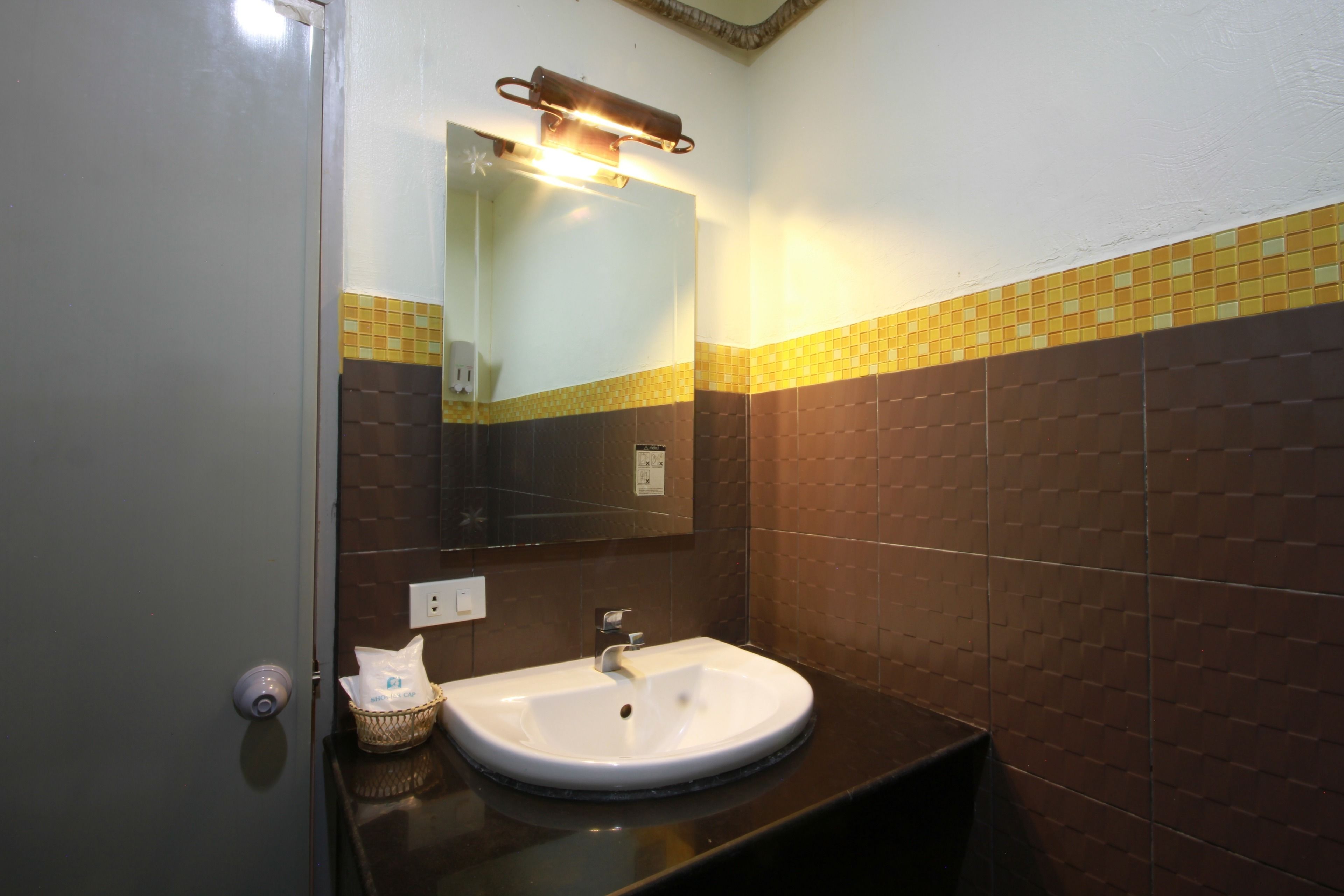 Un baño con un lavamanos blanco, un espejo y un dispensador de toallas.