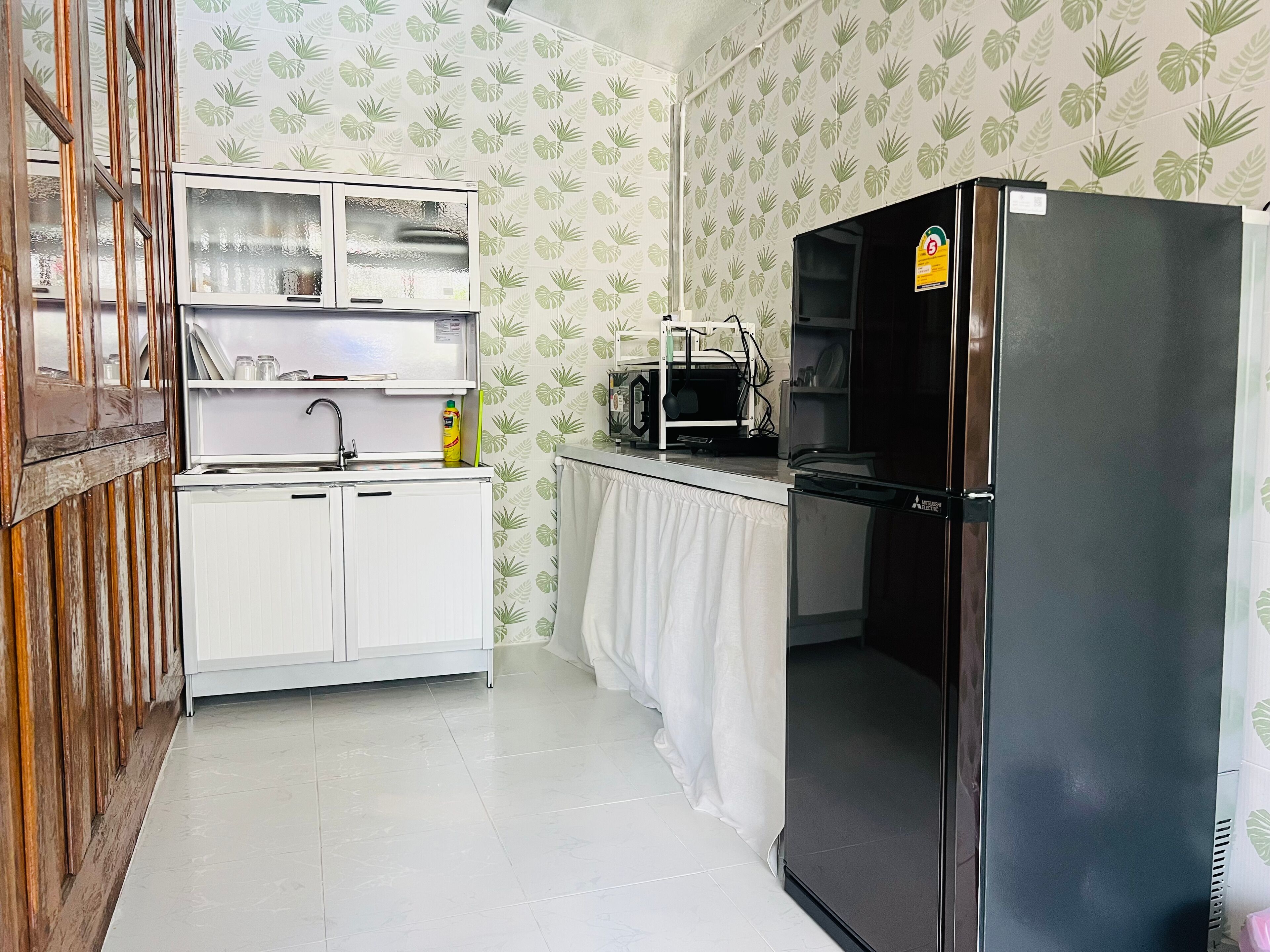 A kitchen with white cabinets, a black refrigerator, a microwave, and a sink.
