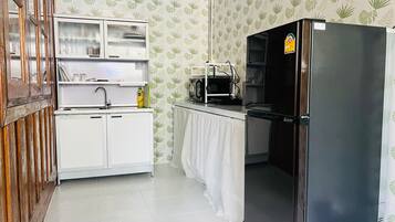 A kitchen with white cabinets, a black refrigerator, a microwave, and a sink.