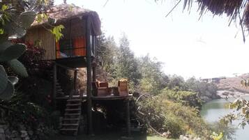 A rustic treehouse with a wooden staircase leading up to a platform with seating.