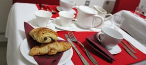 A breakfast setup with croissants and coffee cups on a table with a red napkin and silverware. - Hôtel Bel Air (Paris)