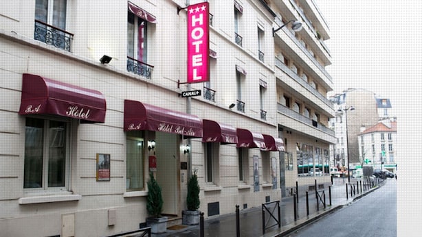 A hotel facade with multiple windows, red awnings, and a prominent "HOTEL" sign. - Hôtel Bel Air (Paris)