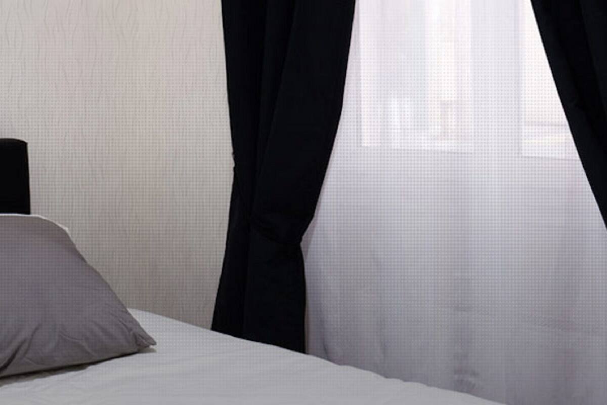 Een bed met een zwart hoofdeinde en een grijs kussen.