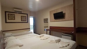 A hotel room with a large bed, a desk, a chair, a flat-screen TV mounted on the wall, and a window with a view. - Porto Praia Hotel (Fortaleza)