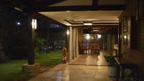 A covered outdoor area with a stone pathway leading to a seating area, surrounded by potted plants and a view of the garden. - Porto Praia Hotel (Fortaleza)