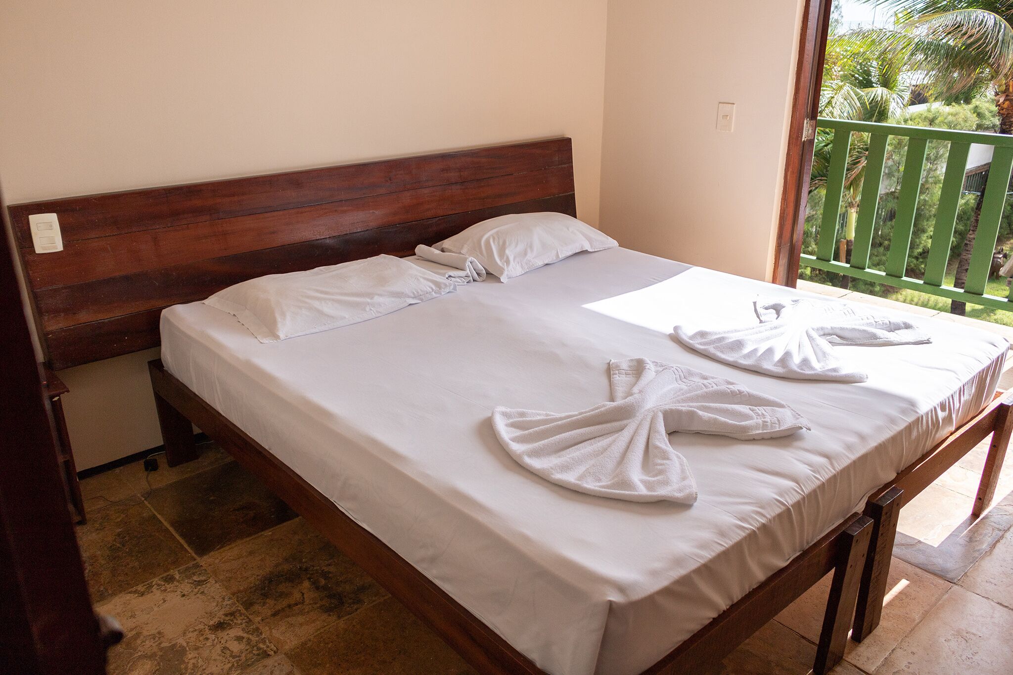 A neatly made bed with white linens and towels arranged on the bed.