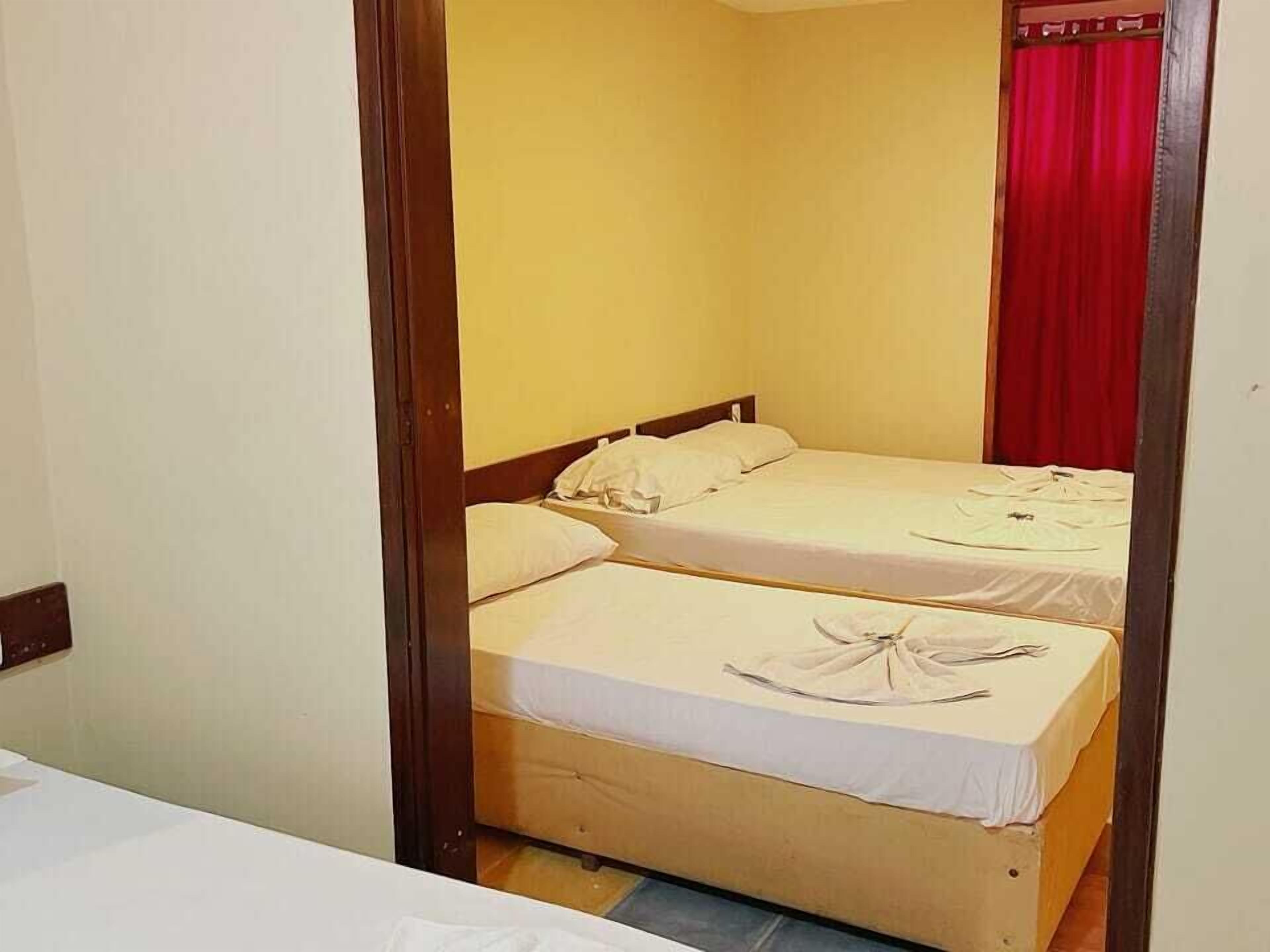 A room with two beds, each with white linens and a wooden headboard.