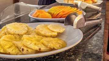 Buffet com diversos alimentos, incluindo fatias de abacaxi e um bolo.