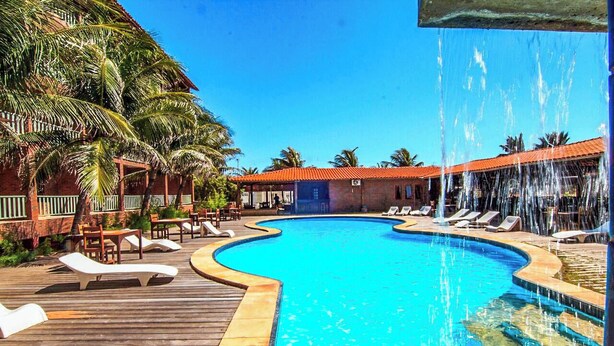 A pool with a wooden deck, lounge chairs, and palm trees. - Porto Praia Hotel (Fortaleza)