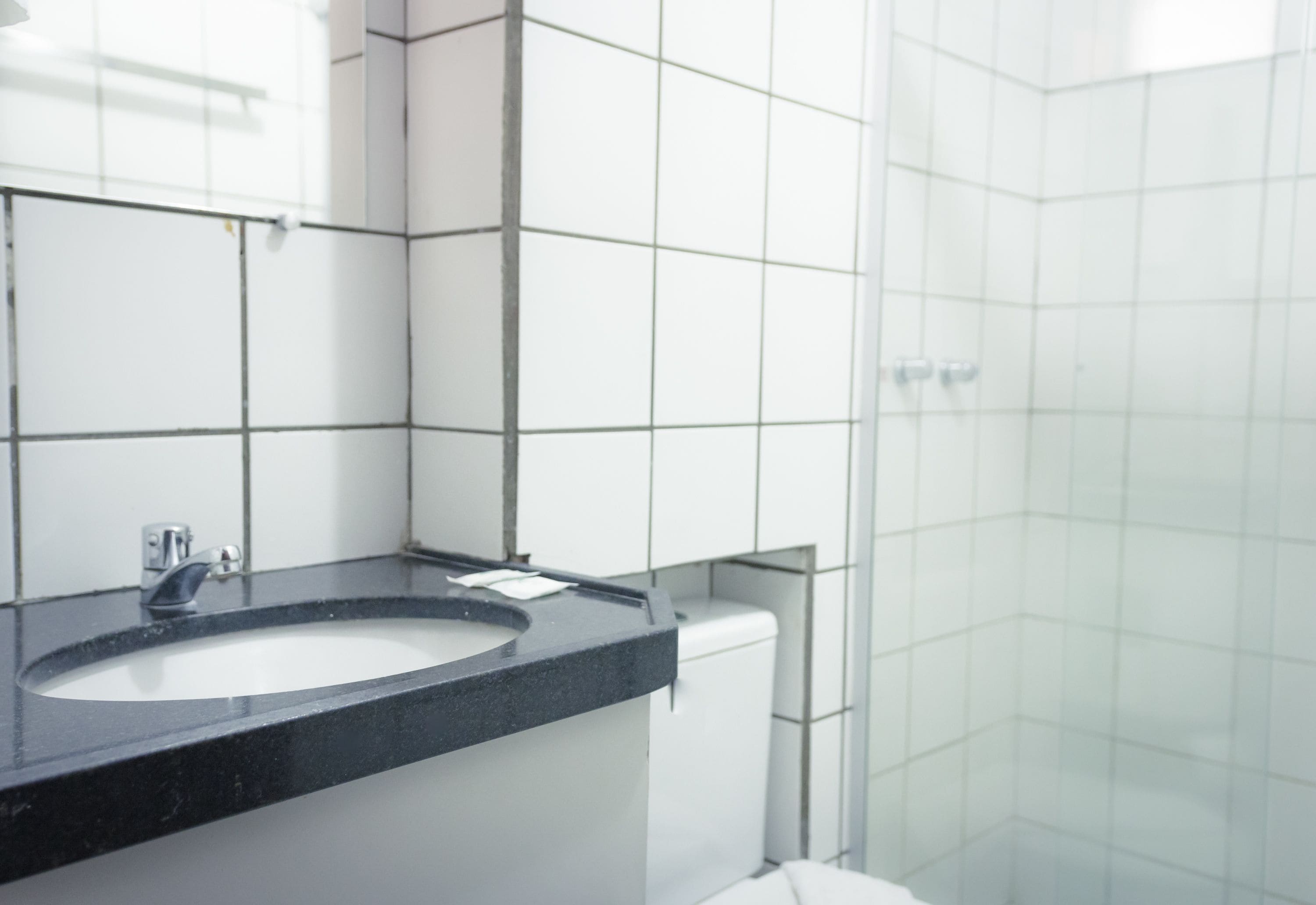 A bathroom with a black sink, white tiles, and a glass shower enclosure.