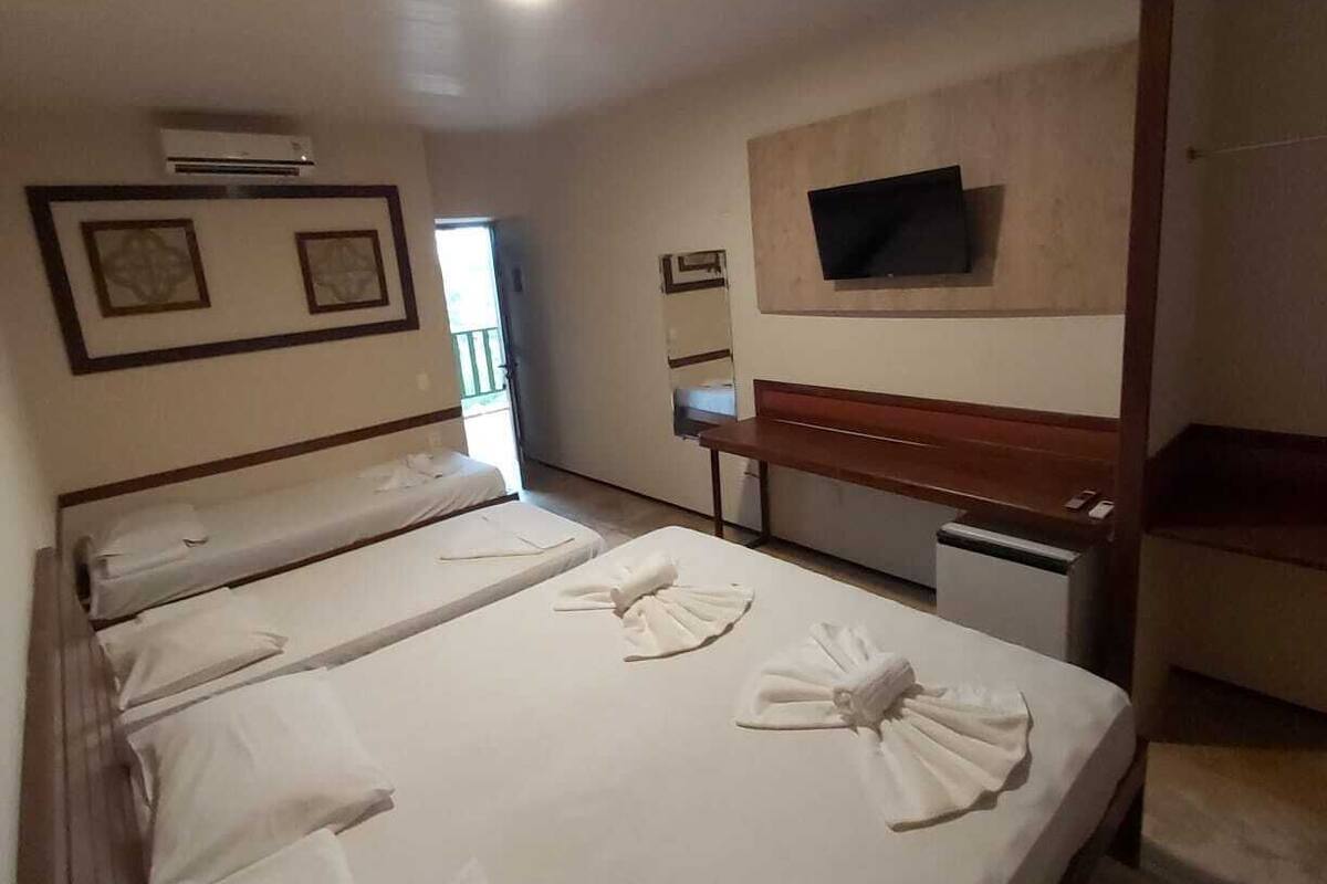 Una habitació d'hotel amb dos llits, un escriptori, una televisió i un aparell d'aire condicionat.