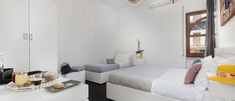 A modern bedroom with a bed, bedside tables, a wardrobe, and a dining area with breakfast items.