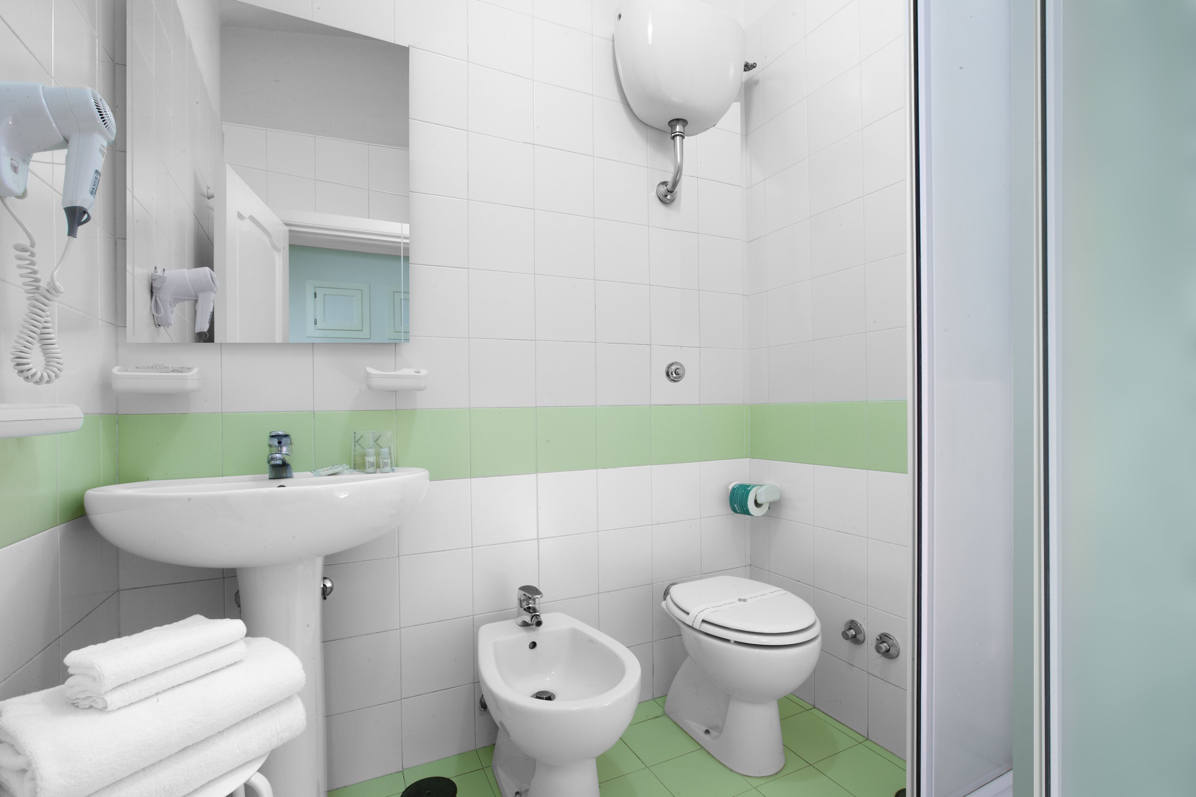 Un baño con lavabo, bidé, inodoro y secador de pelo.
