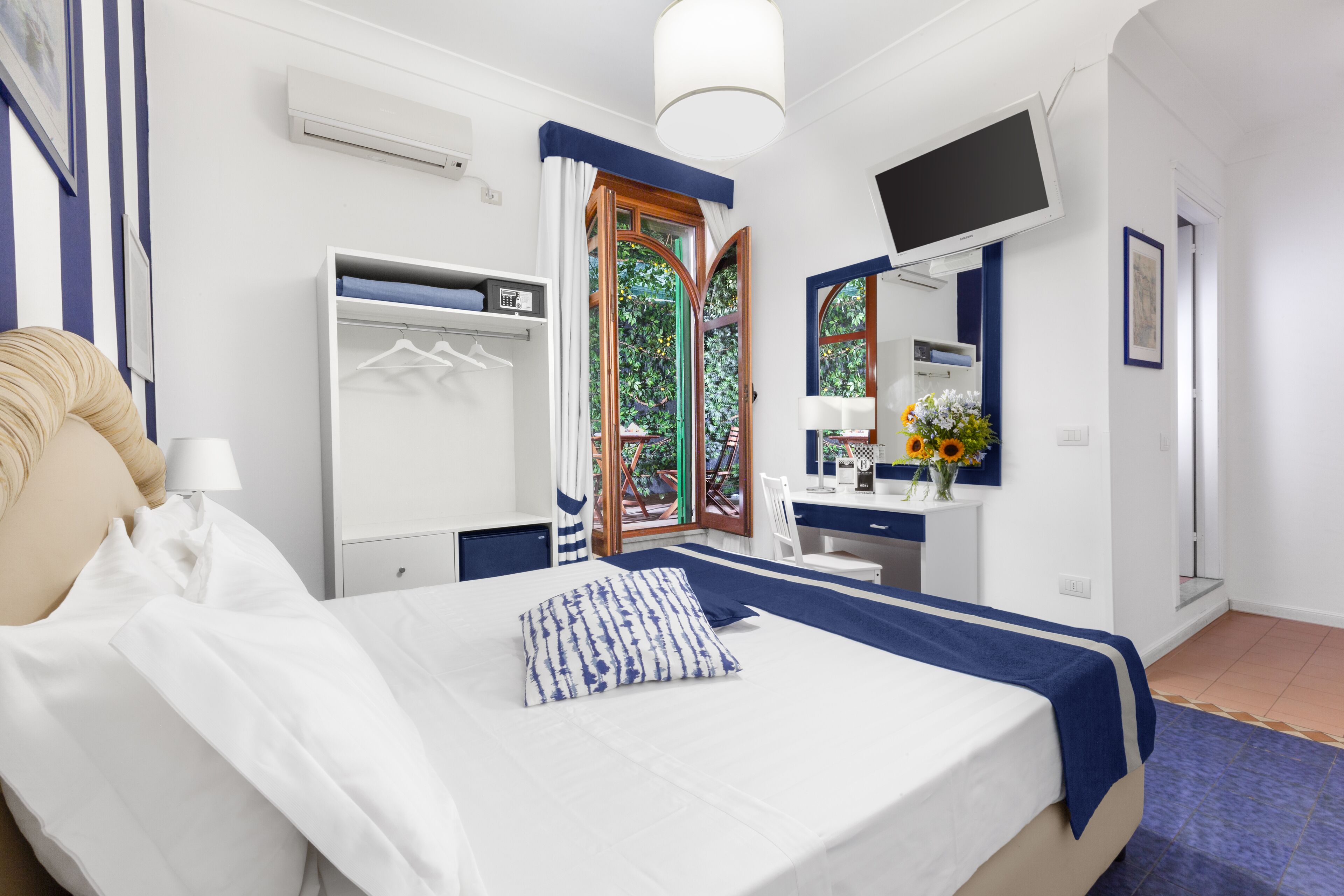 Een moderne slaapkamer met een bed, een bureau, een kledingkast en een televisie.