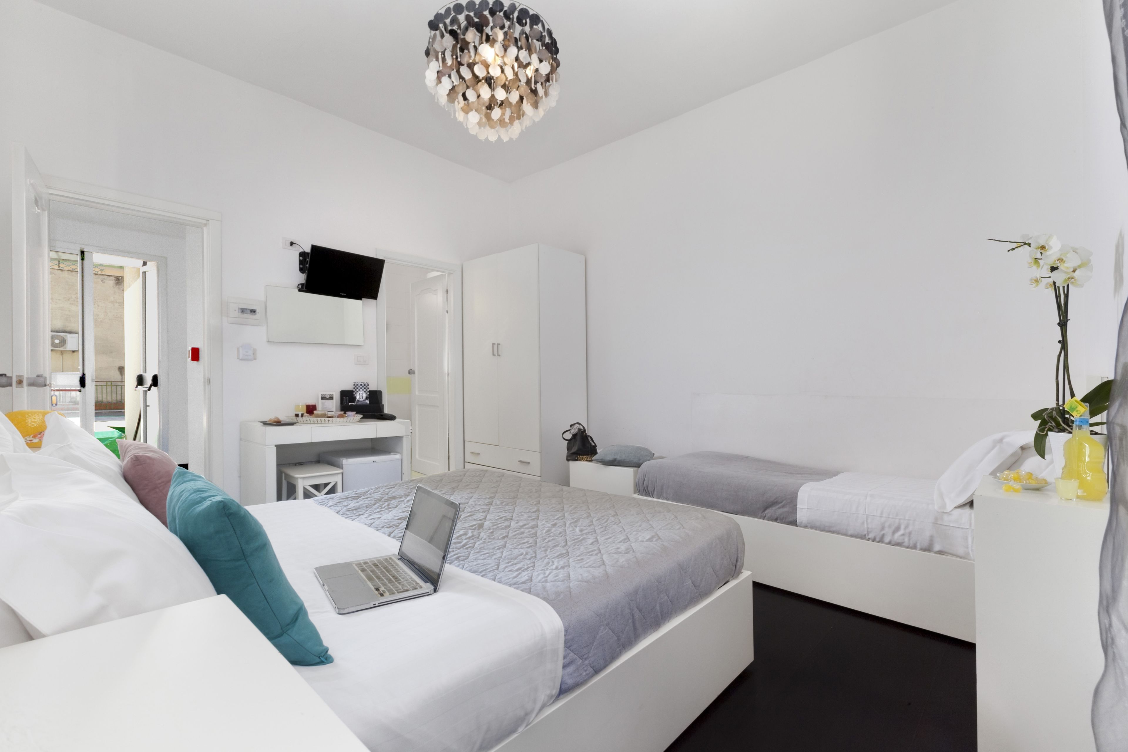 Une chambre d’hôtel moderne équipée d’un lit, d’un bureau, d’une chaise, d’une télévision et d’une petite table agrémentée d’une plante.