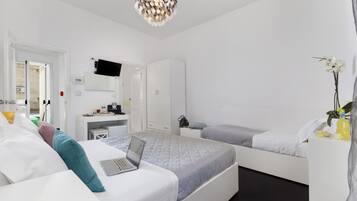Une chambre d’hôtel moderne équipée d’un lit, d’un bureau, d’une chaise, d’une télévision et d’une petite table agrémentée d’une plante.