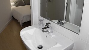 A small, modern bathroom with a white sink, a mirror, and a shower. - Hostalin Diputacion (Barcelona)