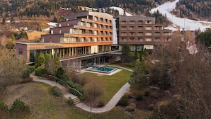 A modern hotel with multiple floors, a swimming pool, and a view of a snowy mountain. - Falkensteiner Hotel Schladming l 4 Star Superior (Schladming)