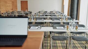 Un salón de conferencias con mesas, sillas y portátiles.