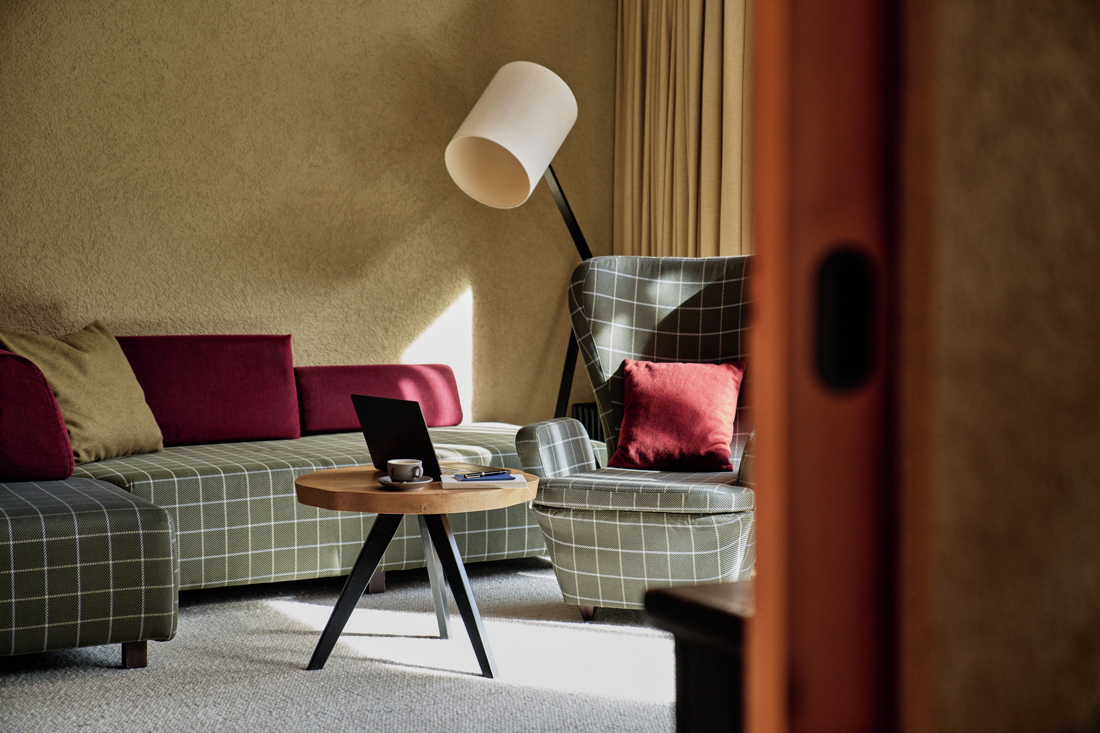 A modern living room with a sofa, a side table with a laptop, and a floor lamp.