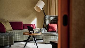 A modern living room with a sofa, a side table with a laptop, and a floor lamp.