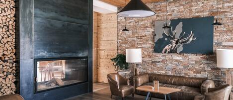 Una sala de estar moderna con pared de piedra, muebles de cuero y chimenea.