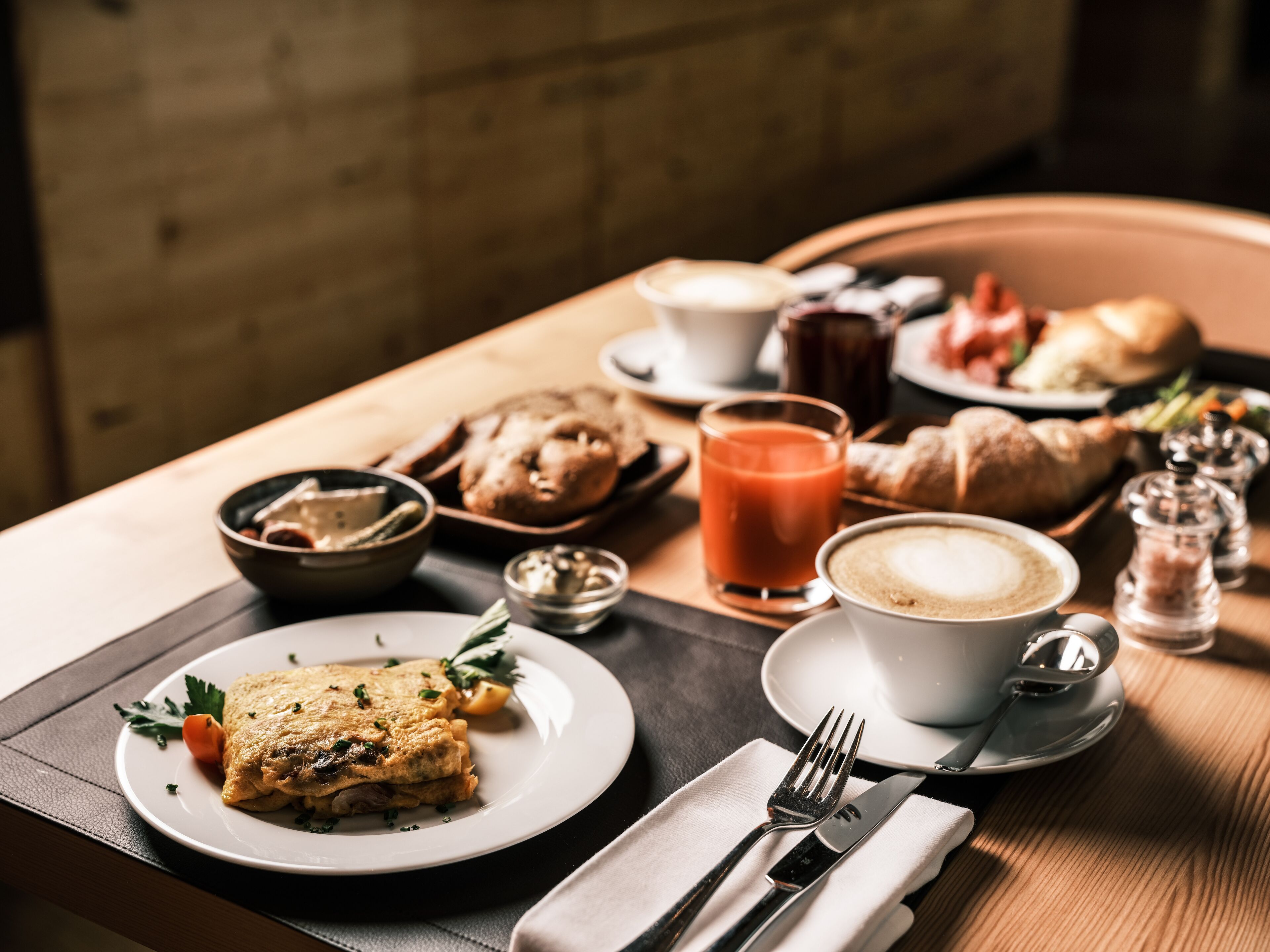 A breakfast setting with a plate of food, a glass of juice, and a cup of coffee on a wooden table.