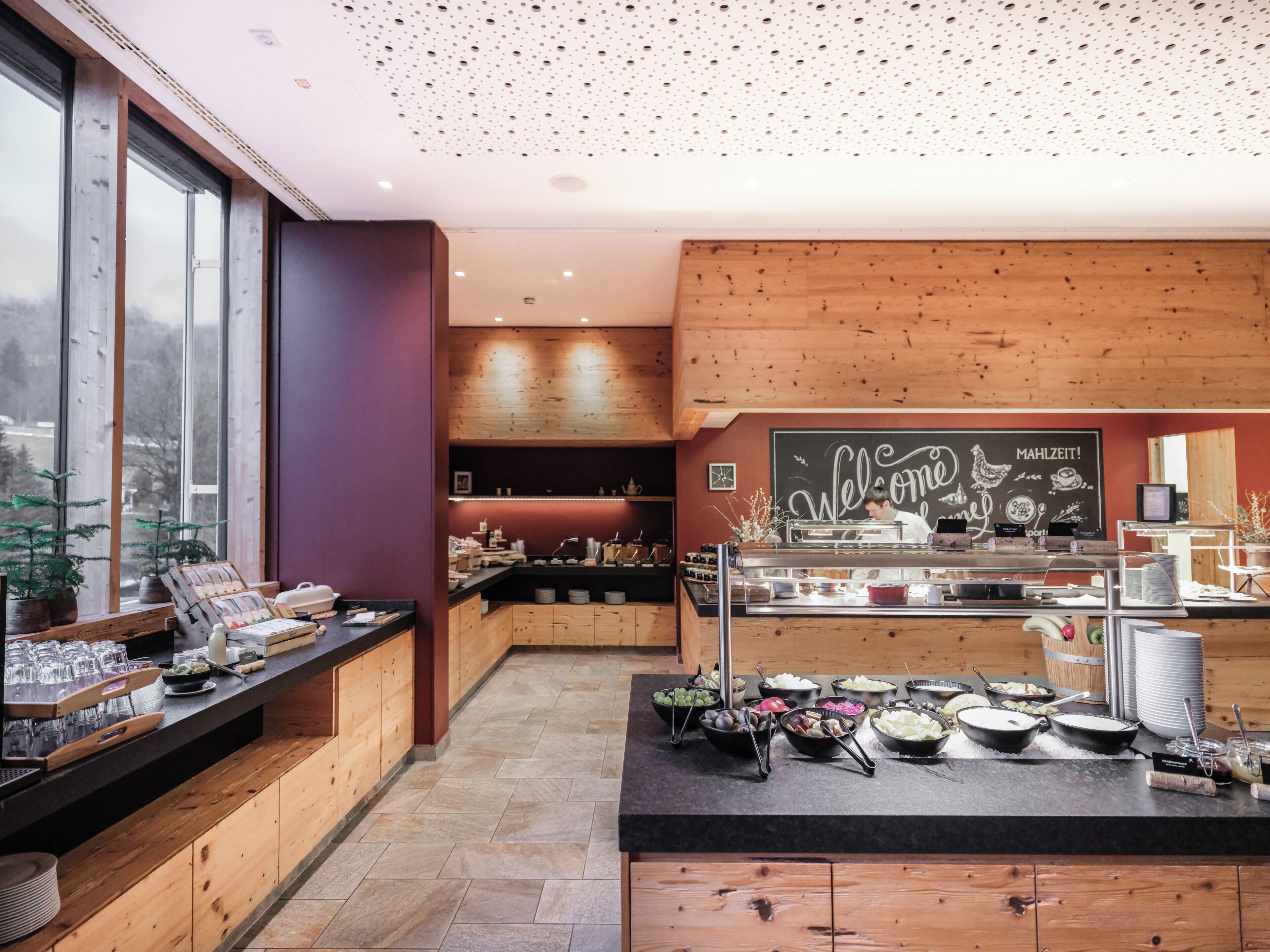 A modern kitchen with wooden cabinets, a black countertop, and a chalkboard sign.