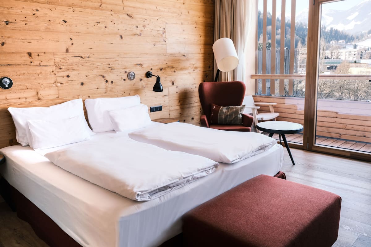 Een kamer met houten vloeren, een bed, een stoel en een tafel.