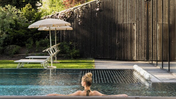 Zona de piscina con vista a montañas, valla de madera y una banca.