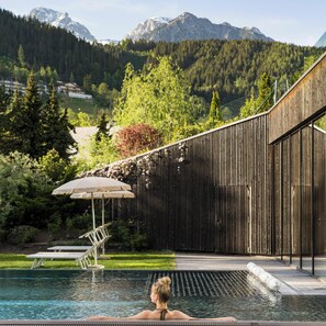 Area piscina con vista sulle montagne, recinzione in legno e una panchina.