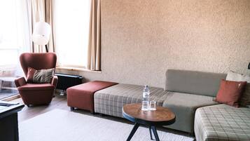 Una sala de estar moderna con un sillón rojo, un sofá gris, una mesita redonda y un radiador.