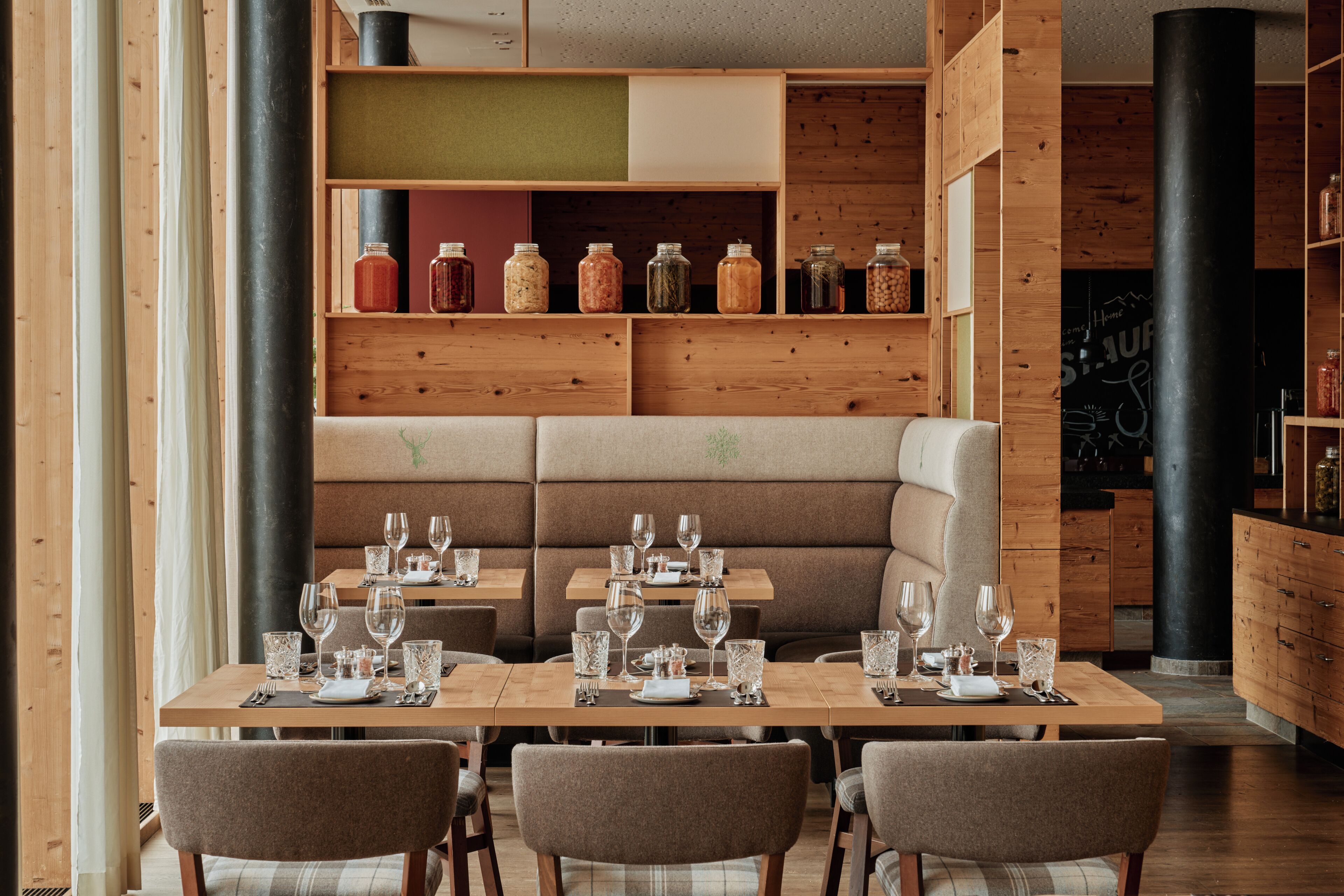 Un ristorante con rivestimenti in legno, un'area salotto centrale e diversi bicchieri sui tavoli.