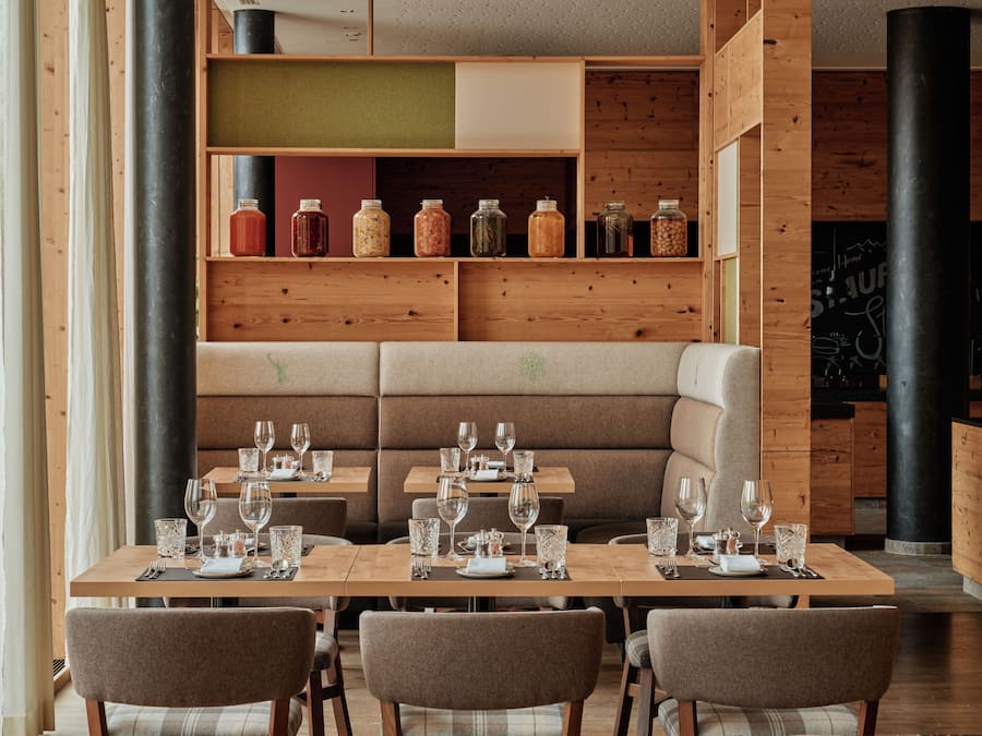 En restaurant med træpaneler, et centralt siddeområde og diverse drikkeglas på bordene.