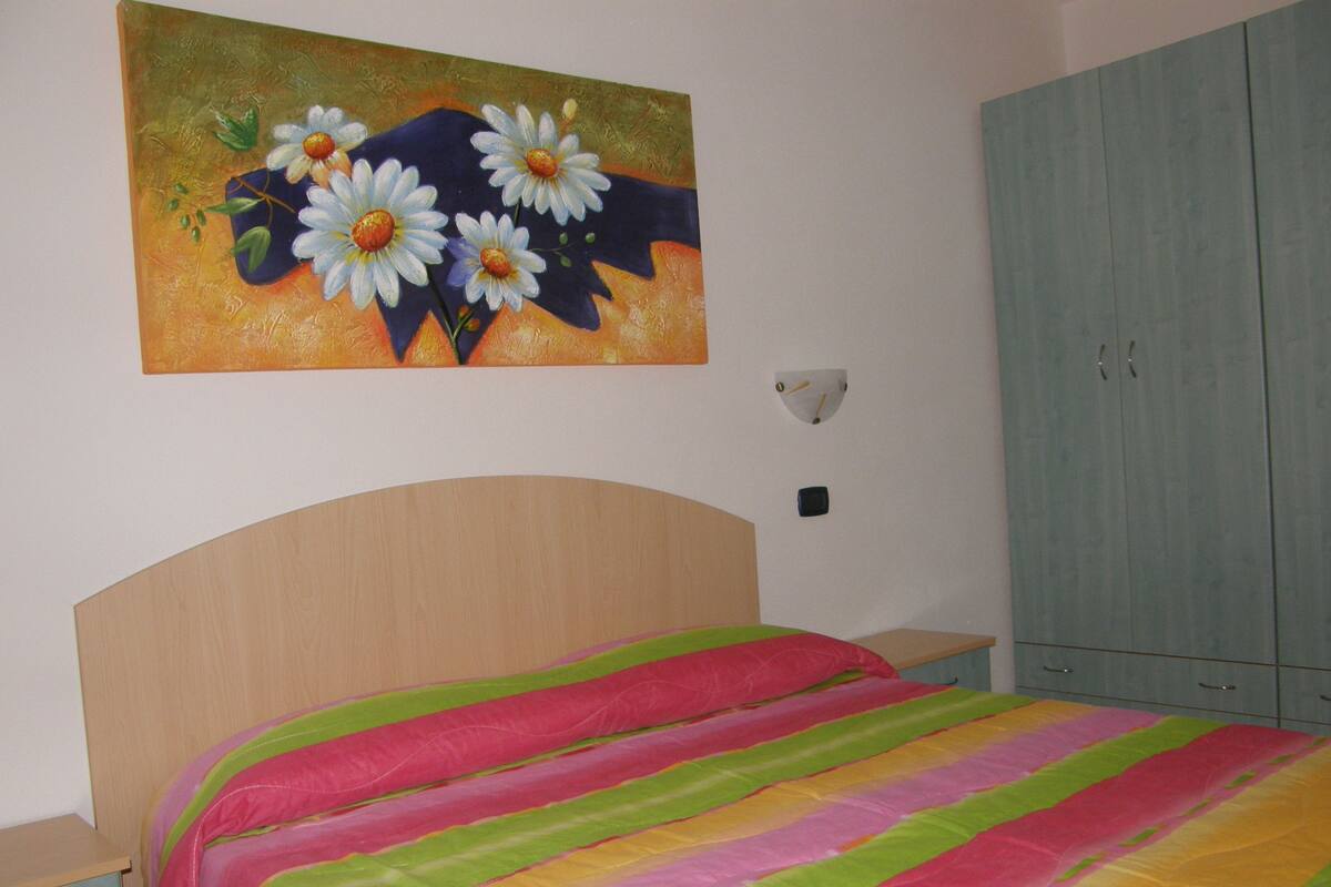 Une chambre à coucher avec un lit, une table de chevet, une armoire et un tableau au mur.