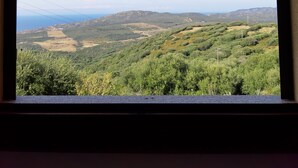 A view from a window overlooking a hilly landscape with greenery and distant mountains. - Appartamenti Paduledda (Trinità d'Agultu e Vignola)