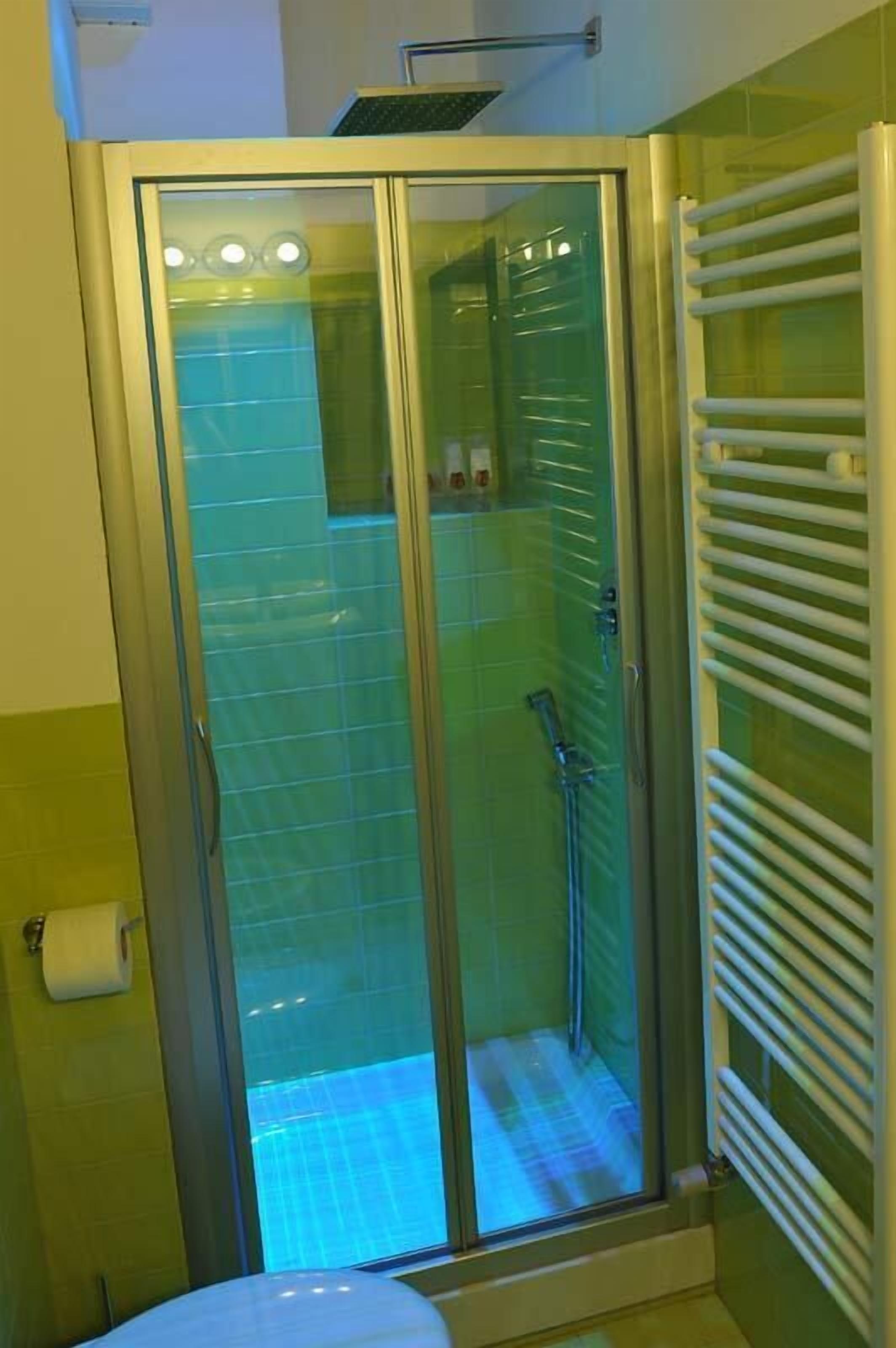 Una cabina de ducha con paredes de vidrio y un perchero a la derecha.