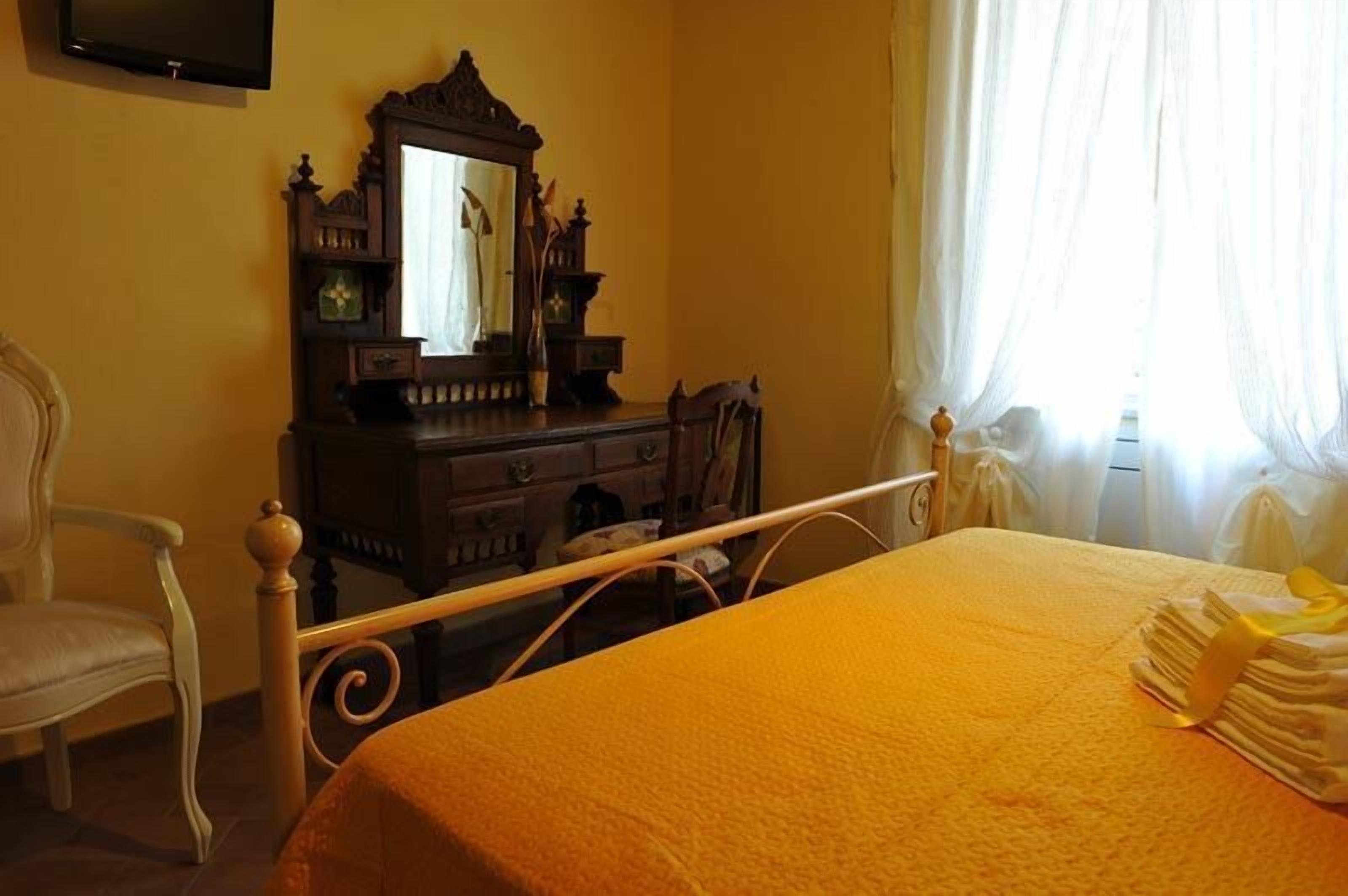 Un dormitorio con cama, cómoda, silla y espejo.