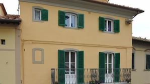Um edifício de vários andares com persianas verdes, varanda e um letreiro com uma nota musical.