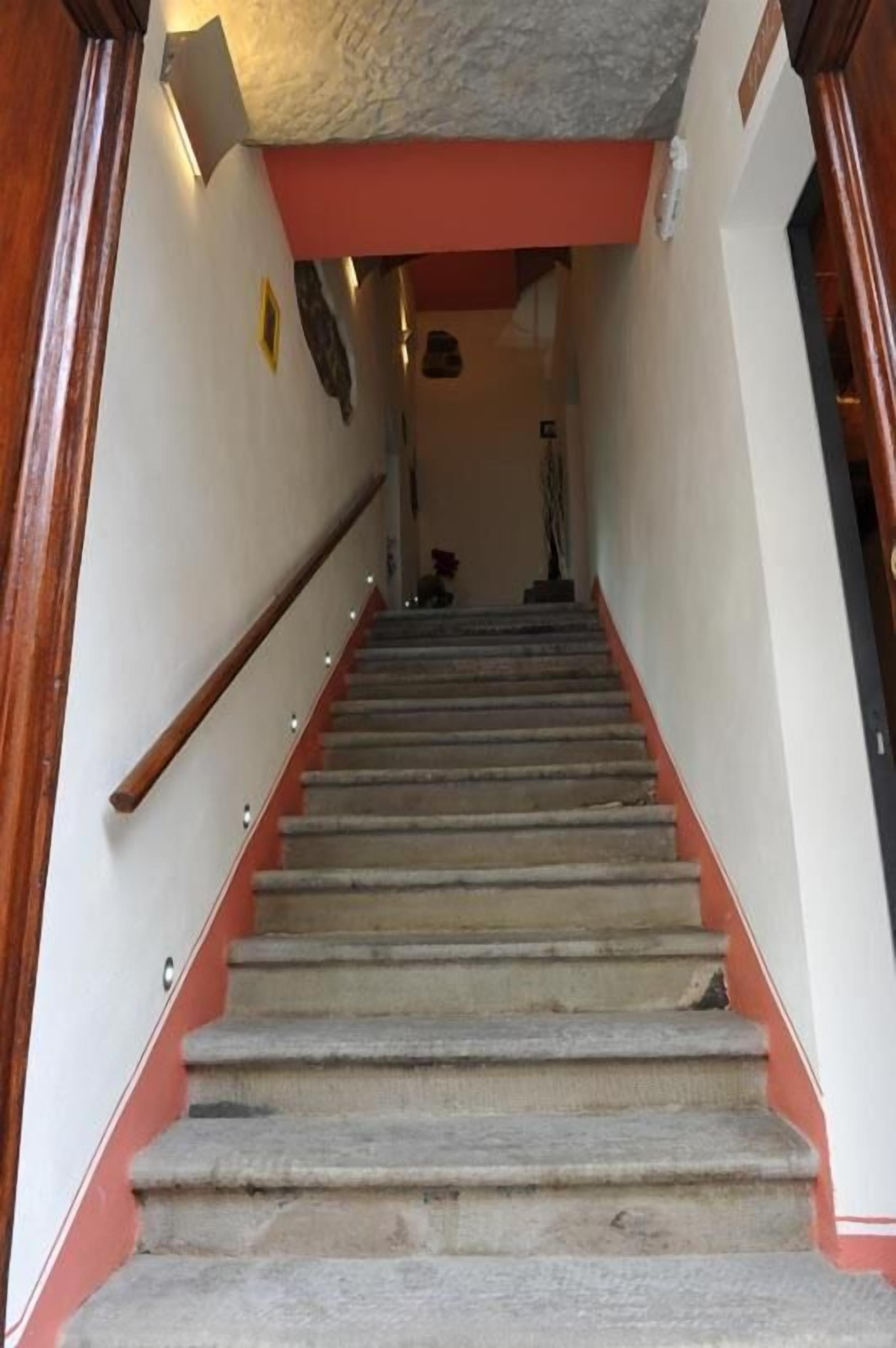 Una scala con ringhiera in legno e parete decorata di rosso.
