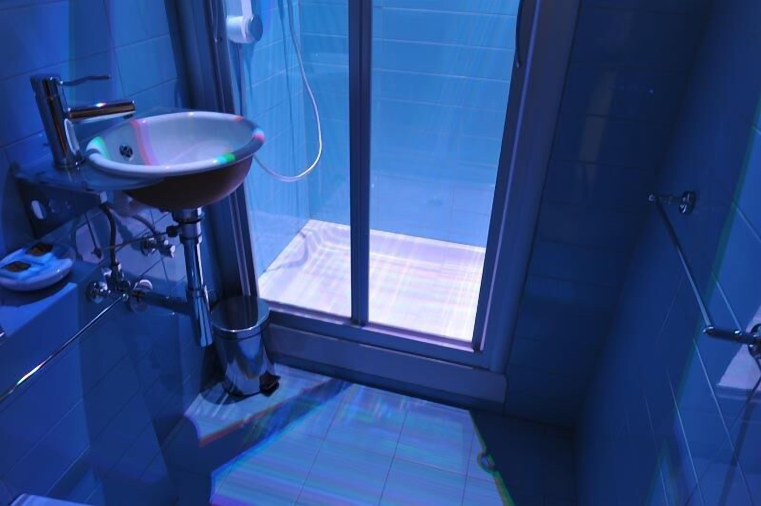 Un baño con cabina de ducha de vidrio, un lavamanos con espejo y suelo de baldosas.
